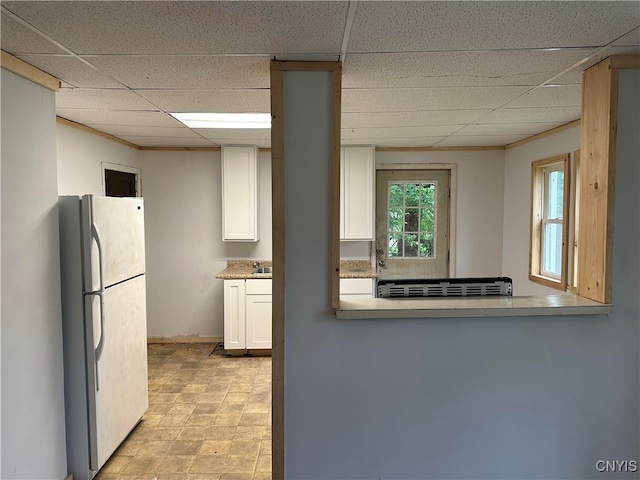 kitchen with white cabinetry, white refrigerator, and a paneled ceiling