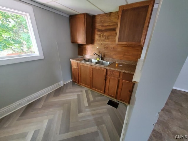 kitchen with a drop ceiling, sink, and light parquet floors