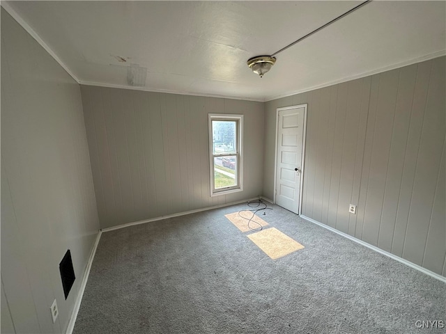 spare room featuring wood walls, carpet flooring, and crown molding