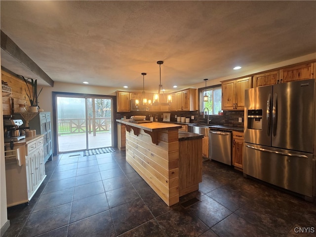 kitchen featuring a kitchen island, appliances with stainless steel finishes, decorative backsplash, and a healthy amount of sunlight