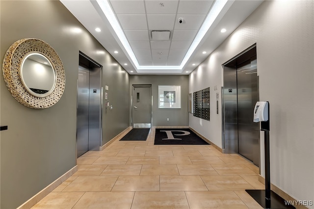 hallway with elevator, a raised ceiling, and a mail area