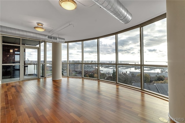 empty room featuring hardwood / wood-style flooring, floor to ceiling windows, and plenty of natural light