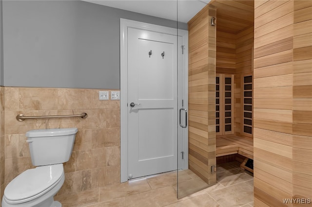 bathroom featuring tile patterned floors, toilet, and tile walls