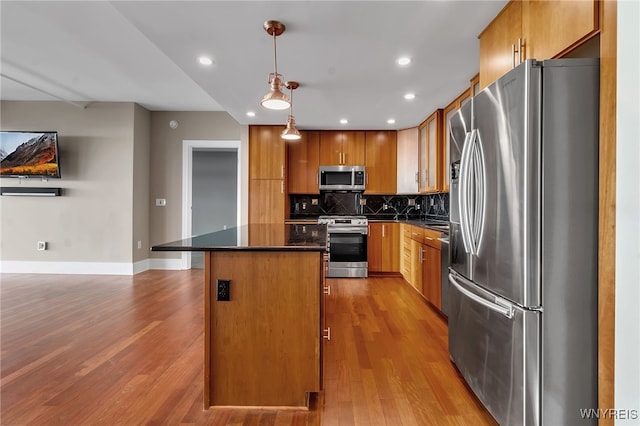 kitchen with tasteful backsplash, light hardwood / wood-style flooring, a kitchen island, pendant lighting, and stainless steel appliances