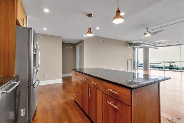 kitchen featuring decorative light fixtures, light hardwood / wood-style flooring, dark stone countertops, ceiling fan, and stainless steel appliances