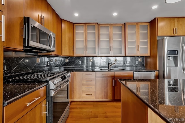 kitchen with sink, decorative backsplash, light hardwood / wood-style flooring, and appliances with stainless steel finishes