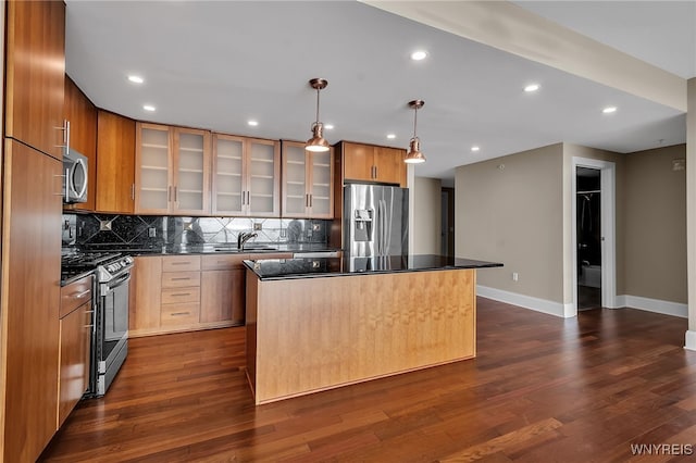 kitchen featuring pendant lighting, appliances with stainless steel finishes, a center island, and sink