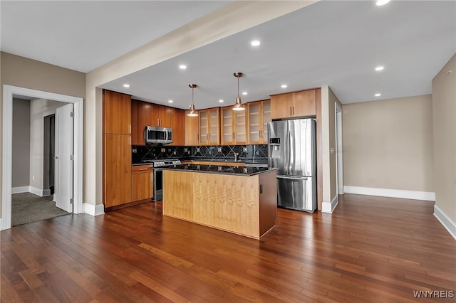 kitchen with hanging light fixtures, backsplash, stainless steel appliances, a center island, and dark hardwood / wood-style flooring