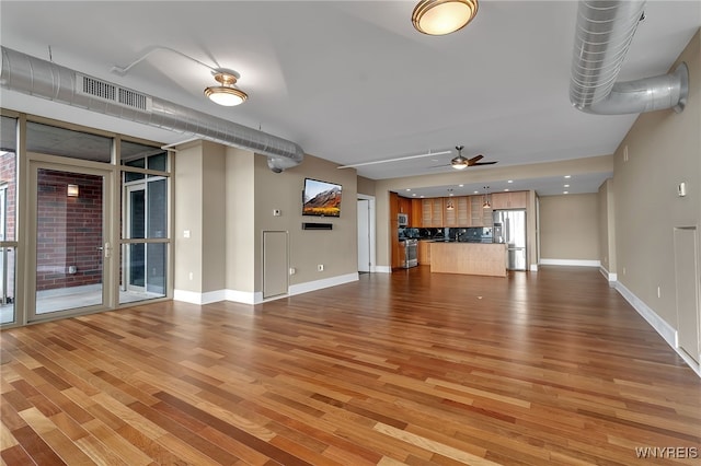 unfurnished living room featuring wood-type flooring and ceiling fan