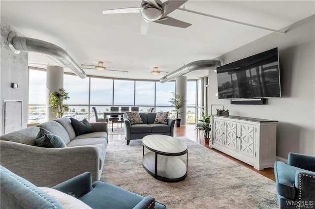 living room featuring wood-type flooring, expansive windows, and ceiling fan