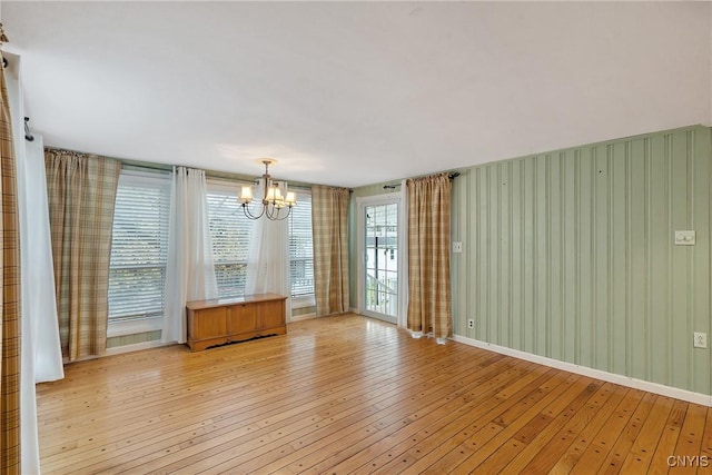 unfurnished room featuring light wood-type flooring and an inviting chandelier