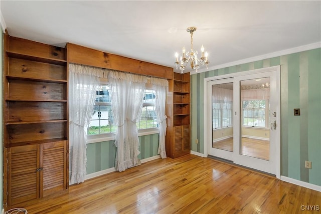 doorway to outside featuring plenty of natural light, light hardwood / wood-style floors, crown molding, and a chandelier