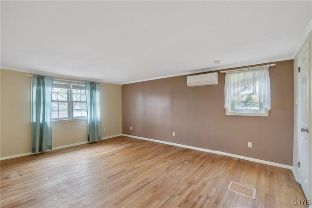 spare room featuring a wall unit AC, ornamental molding, and light wood-type flooring