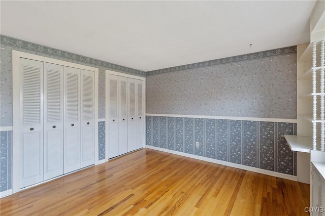 unfurnished bedroom featuring two closets and hardwood / wood-style flooring