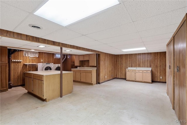 kitchen featuring a paneled ceiling, wood walls, and washing machine and clothes dryer