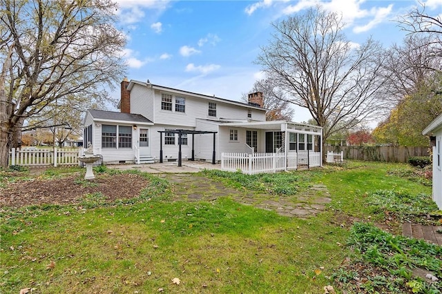 rear view of property featuring a pergola, a sunroom, and a lawn