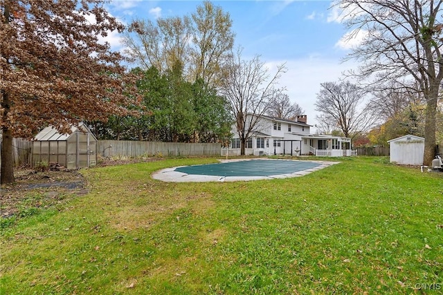 view of yard with a sunroom, a patio area, a storage shed, and a covered pool