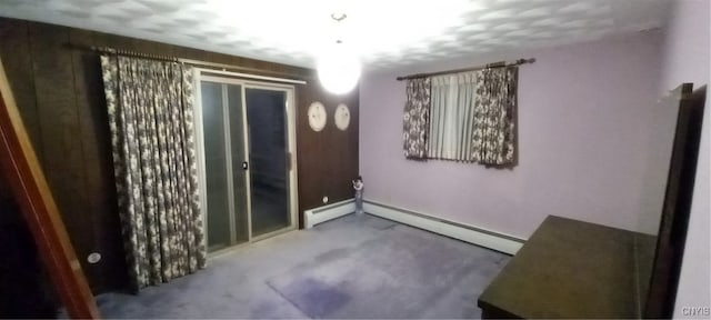 empty room featuring a baseboard heating unit and carpet floors