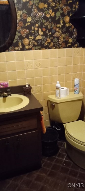 bathroom featuring toilet, vanity, tile walls, and tile patterned floors