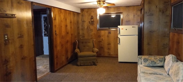 interior space featuring wooden walls, ceiling fan, and carpet floors