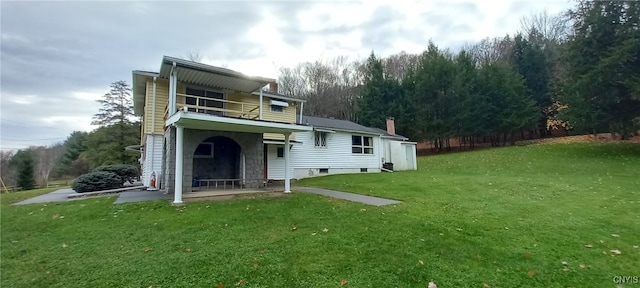 rear view of property featuring a balcony and a yard