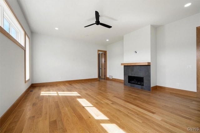 unfurnished living room featuring a fireplace, ceiling fan, and light hardwood / wood-style flooring