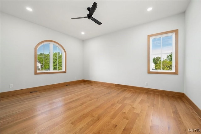 empty room featuring light wood-type flooring, ceiling fan, and a wealth of natural light