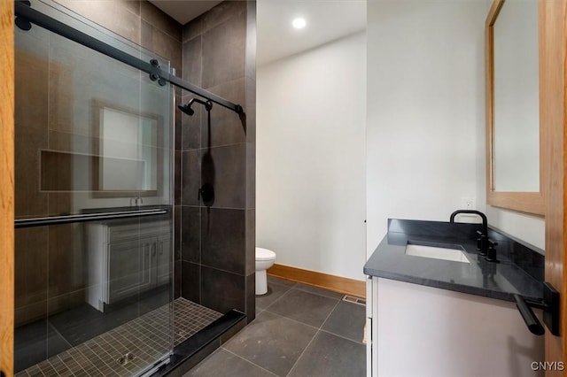 bathroom with toilet, tile patterned flooring, a shower with door, and vanity