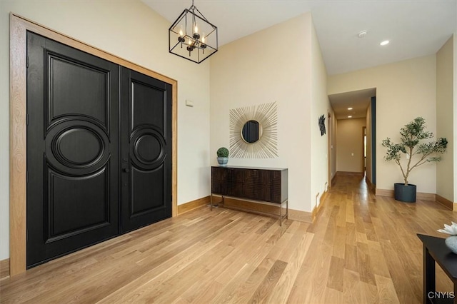 entrance foyer with light wood-type flooring and a notable chandelier