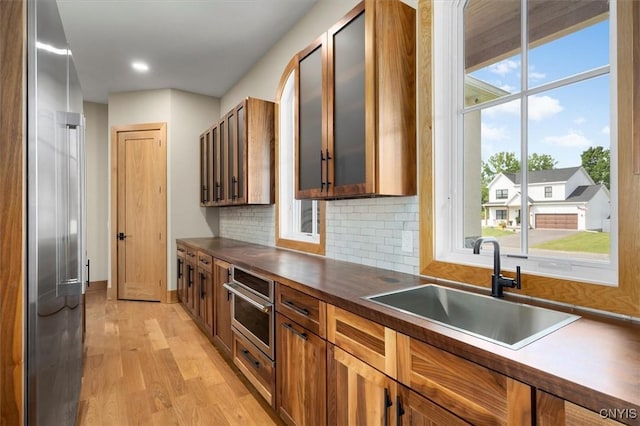 kitchen with light hardwood / wood-style flooring, appliances with stainless steel finishes, backsplash, and sink