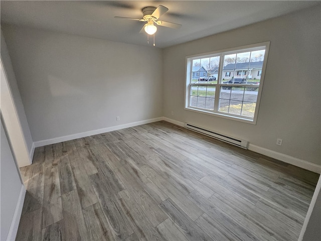 unfurnished room with ceiling fan, baseboard heating, and light wood-type flooring