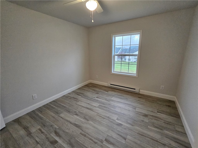 spare room featuring ceiling fan, light wood-type flooring, and a baseboard heating unit