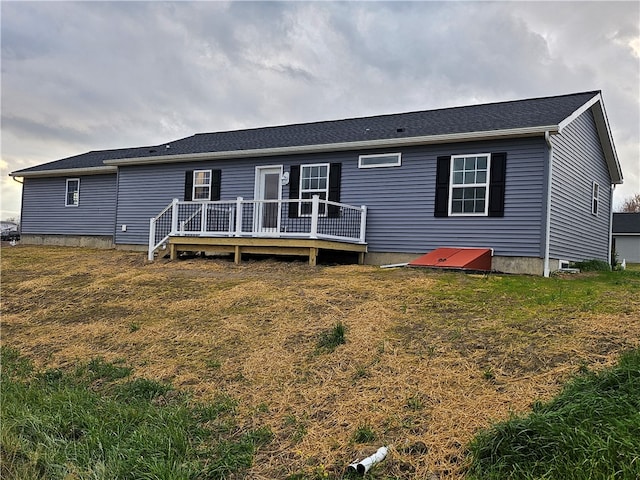 rear view of property featuring a lawn and a deck