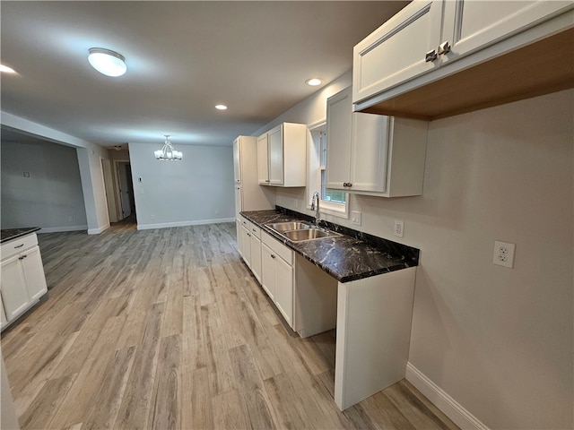 kitchen with white cabinets, light wood-type flooring, sink, and decorative light fixtures