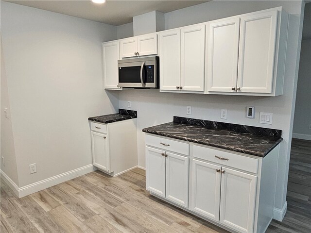 kitchen featuring white cabinetry, light wood-type flooring, and dark stone counters