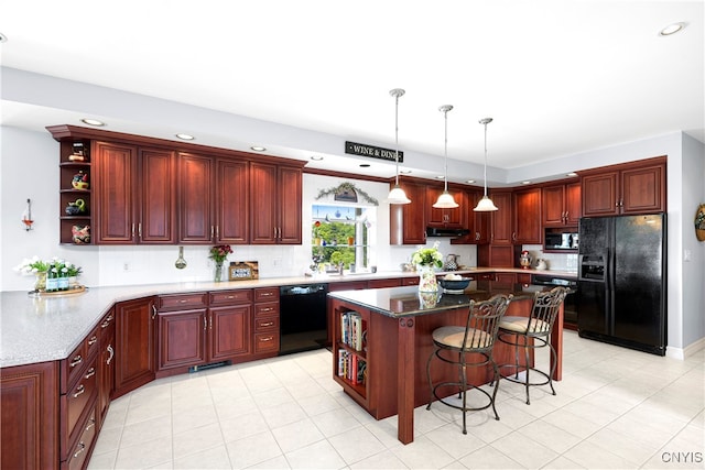 kitchen featuring dark stone counters, black appliances, a breakfast bar area, a kitchen island, and pendant lighting