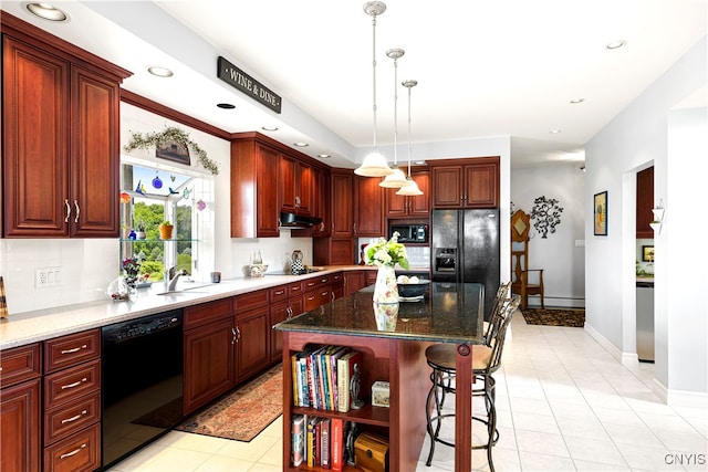 kitchen with dark stone counters, hanging light fixtures, black appliances, light tile patterned floors, and a kitchen island