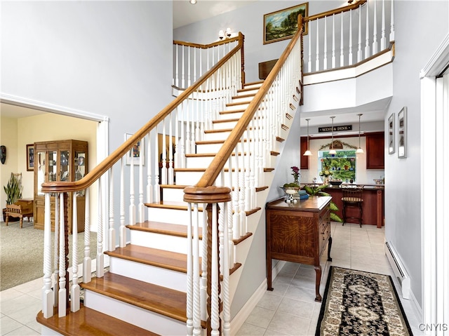 stairway with baseboard heating, tile patterned flooring, and a high ceiling