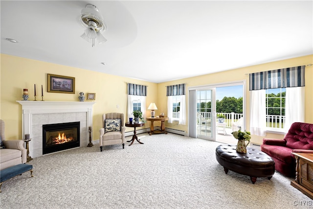 carpeted living room with a tiled fireplace, ceiling fan, and a baseboard radiator