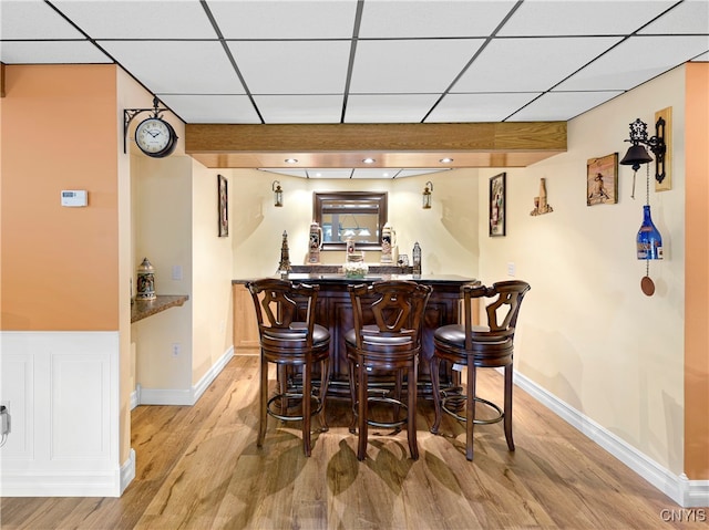 bar featuring light wood-type flooring and a drop ceiling