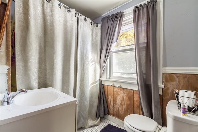 bathroom with tile patterned floors, wooden walls, toilet, and sink