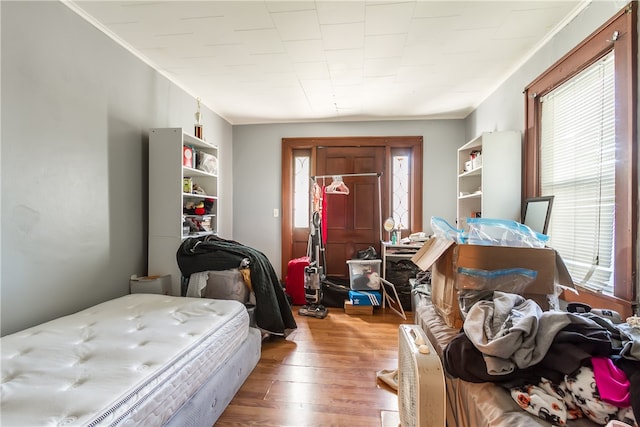 bedroom with ornamental molding and hardwood / wood-style floors