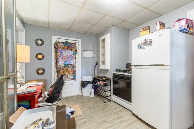 kitchen with white appliances, white cabinetry, light wood-type flooring, and a drop ceiling