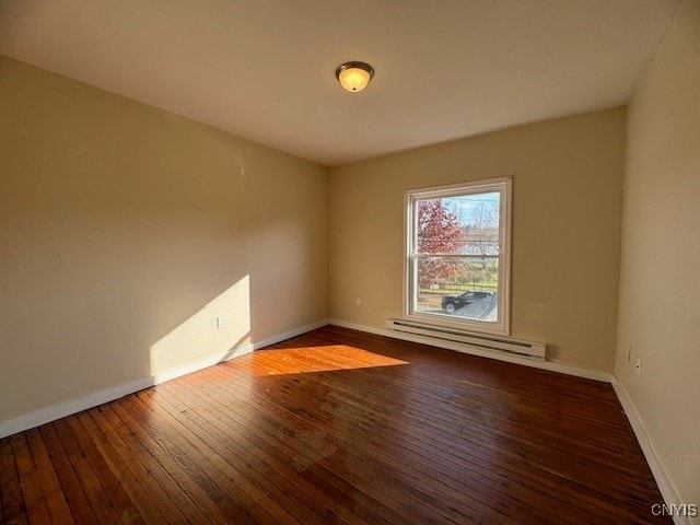 empty room featuring a baseboard heating unit and dark hardwood / wood-style flooring