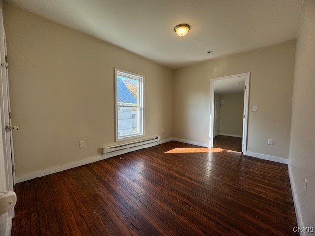 unfurnished room with dark hardwood / wood-style floors and a baseboard radiator