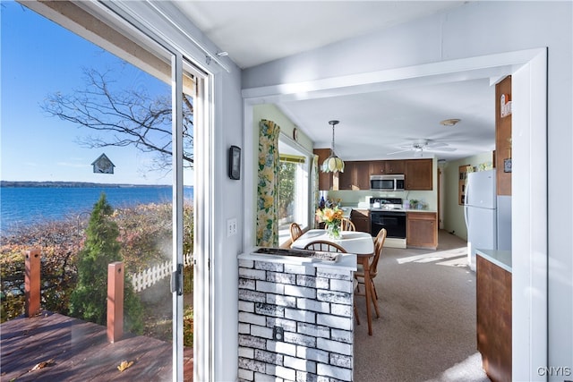 dining area featuring ceiling fan, a water view, and carpet