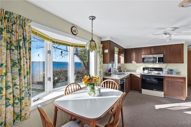 kitchen with white electric range oven, black dishwasher, pendant lighting, sink, and a water view