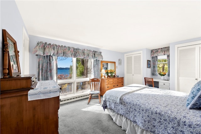 bedroom featuring two closets, carpet flooring, and a baseboard heating unit