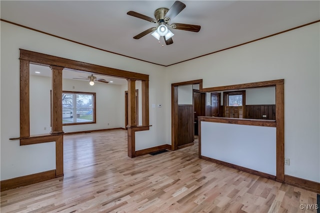 empty room featuring ornate columns, light hardwood / wood-style flooring, ornamental molding, and ceiling fan