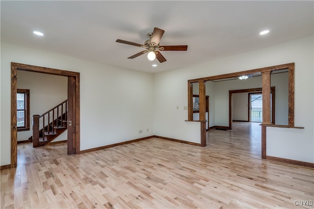 empty room featuring ornate columns, light hardwood / wood-style flooring, and ceiling fan